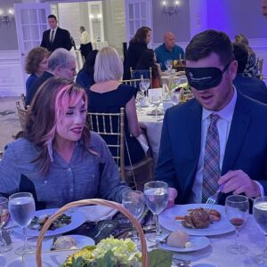 Two attendees enjoy Dining in the Dark. One individual wears learning shades.